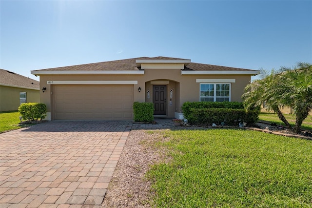 view of front facade with a garage, a front yard, decorative driveway, and stucco siding