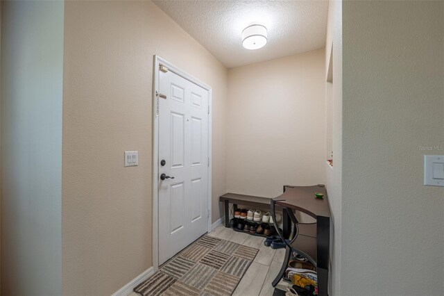 entryway featuring a textured ceiling and baseboards