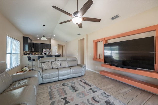 living area featuring visible vents, baseboards, lofted ceiling, ceiling fan, and wood tiled floor