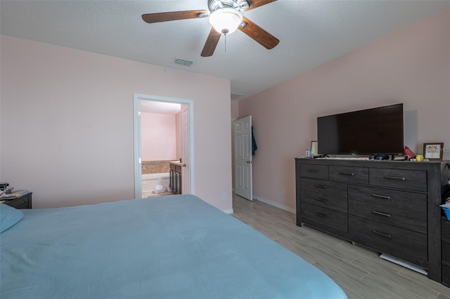 bedroom with a ceiling fan, baseboards, visible vents, light wood-style floors, and ensuite bath