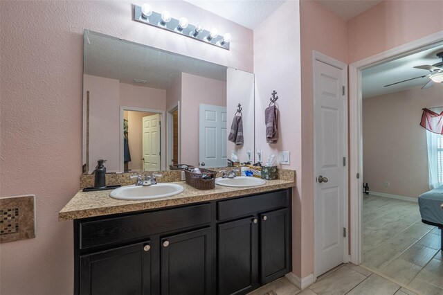 full bathroom featuring double vanity, baseboards, a ceiling fan, and a sink