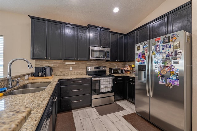 kitchen featuring stainless steel appliances, light stone counters, backsplash, and a sink