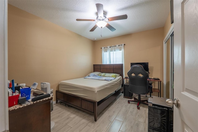 bedroom featuring light wood finished floors, a ceiling fan, and a textured ceiling