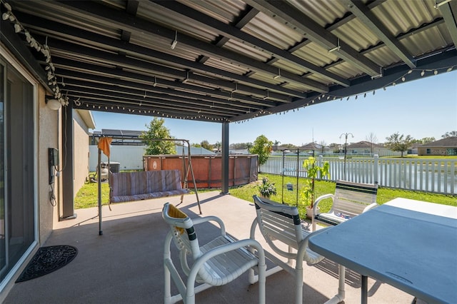 view of patio / terrace with outdoor dining area, a water view, a jacuzzi, and a fenced backyard