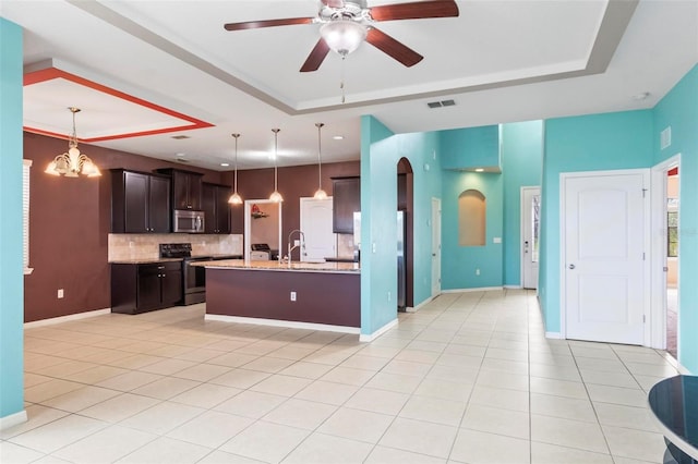 kitchen featuring light tile patterned floors, a tray ceiling, arched walkways, dark brown cabinets, and appliances with stainless steel finishes