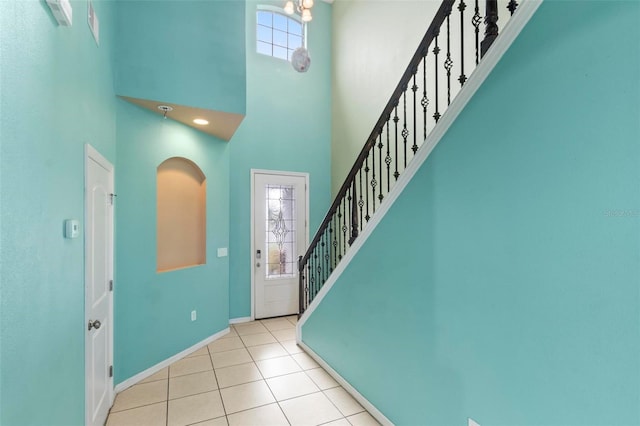 tiled foyer entrance with baseboards, plenty of natural light, a towering ceiling, and stairway