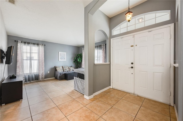 entryway featuring light tile patterned floors, visible vents, arched walkways, and baseboards