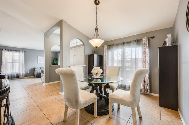 dining space featuring plenty of natural light, arched walkways, and light tile patterned flooring