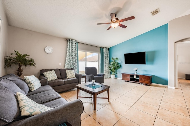 living area featuring vaulted ceiling, visible vents, ceiling fan, and light tile patterned floors