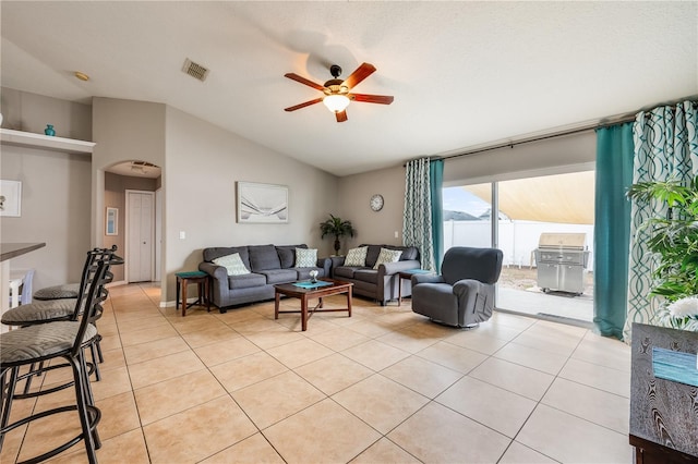 living room featuring arched walkways, light tile patterned floors, visible vents, a ceiling fan, and vaulted ceiling