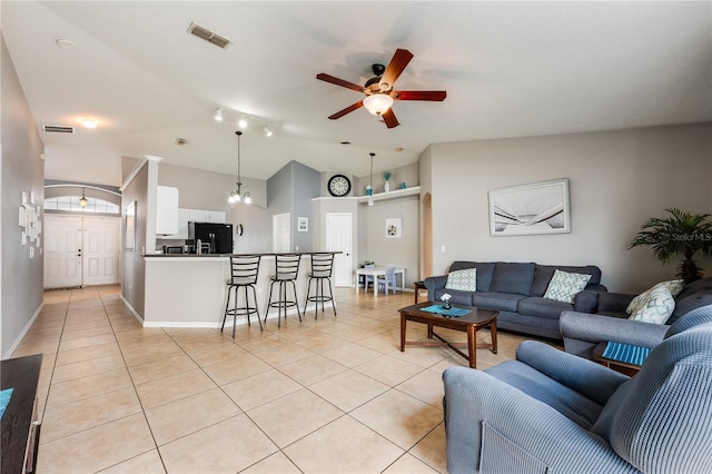 living area with vaulted ceiling, light tile patterned flooring, visible vents, and a ceiling fan