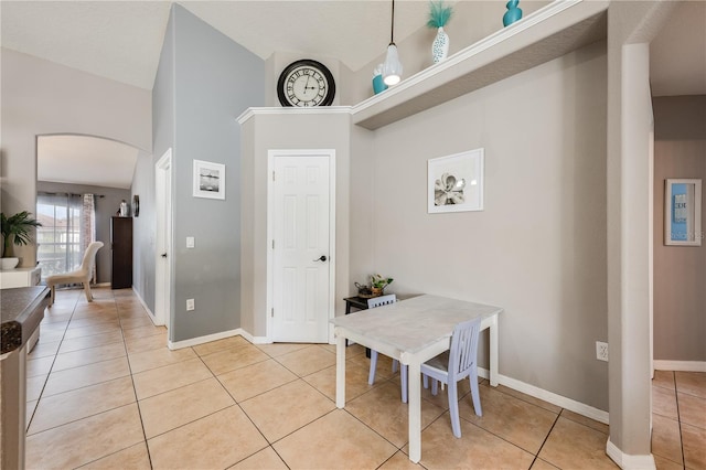 dining space with arched walkways, baseboards, and light tile patterned floors