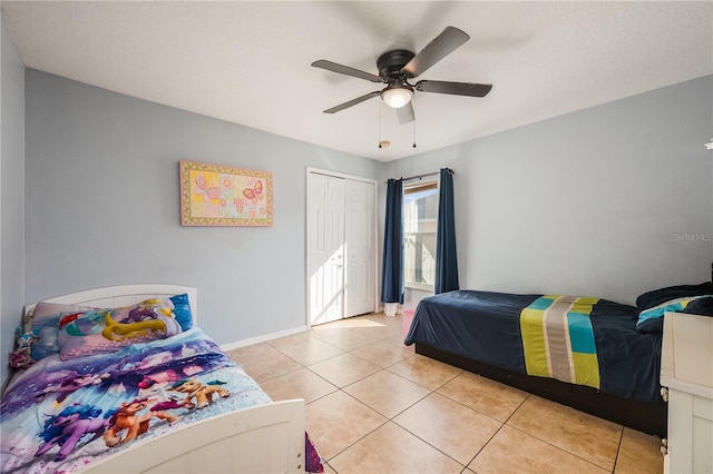 bedroom featuring ceiling fan, a closet, light tile patterned flooring, and baseboards