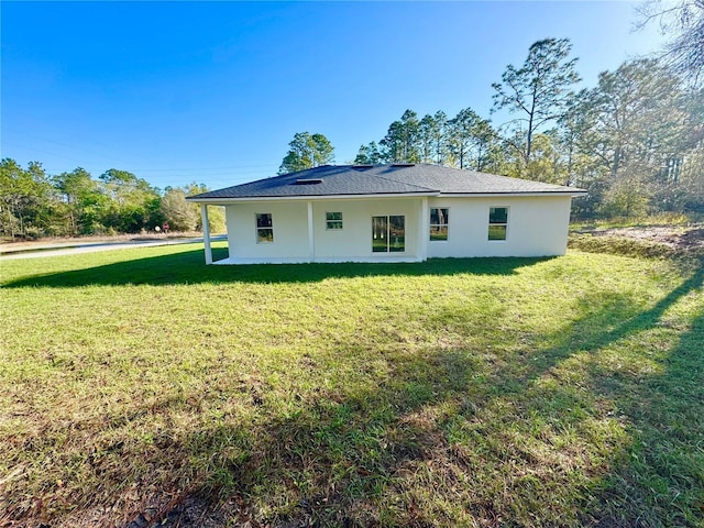 rear view of house with a yard and stucco siding