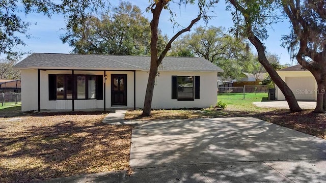 ranch-style house with a shingled roof, fence, and stucco siding