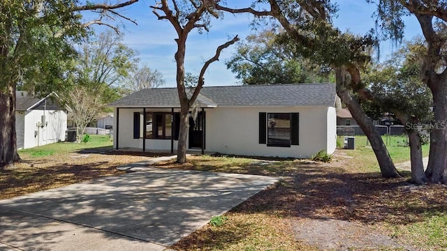 ranch-style home with a front lawn, stucco siding, fence, and central air condition unit