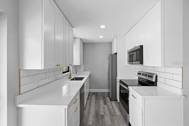 kitchen featuring appliances with stainless steel finishes, a sink, white cabinetry, and decorative backsplash