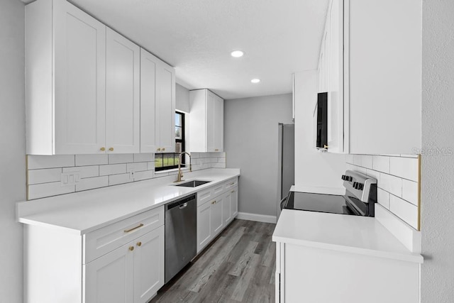 kitchen featuring stainless steel appliances, wood finished floors, a sink, and white cabinets