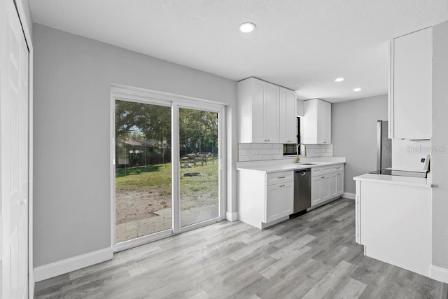 kitchen with light wood finished floors, backsplash, light countertops, stainless steel dishwasher, and a sink