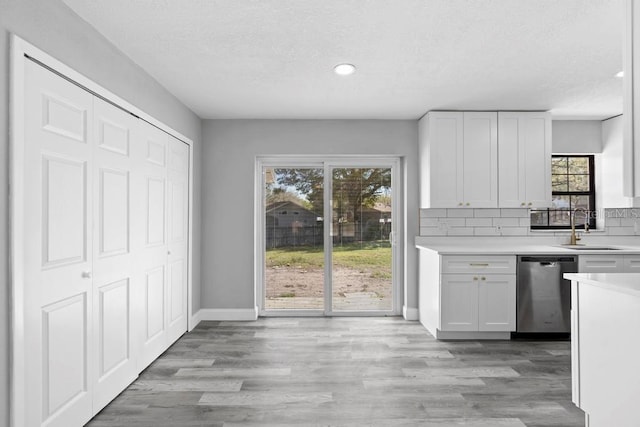 kitchen with light countertops, dishwasher, light wood finished floors, and a sink