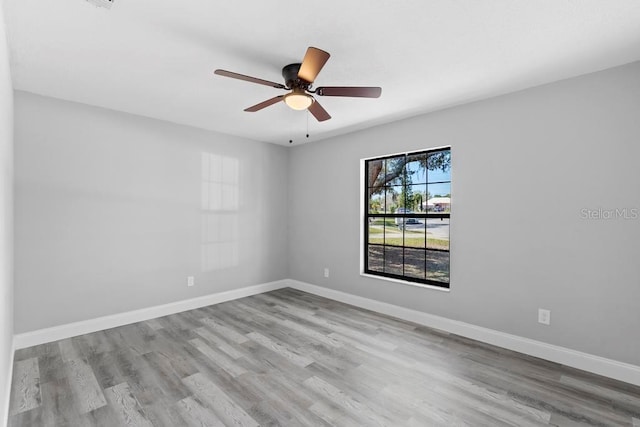 empty room featuring a ceiling fan, baseboards, and wood finished floors