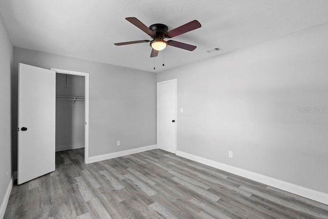 unfurnished bedroom with a closet, visible vents, baseboards, and wood finished floors