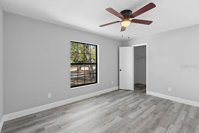 unfurnished room with wood finished floors, a ceiling fan, and baseboards