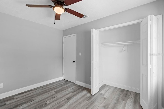 unfurnished bedroom with visible vents, baseboards, ceiling fan, wood finished floors, and a closet