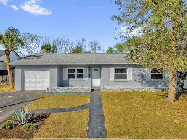 ranch-style home with roof with shingles, an attached garage, stucco siding, a front lawn, and aphalt driveway