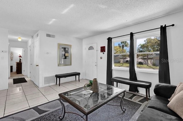 living room featuring visible vents, a textured ceiling, and light tile patterned flooring