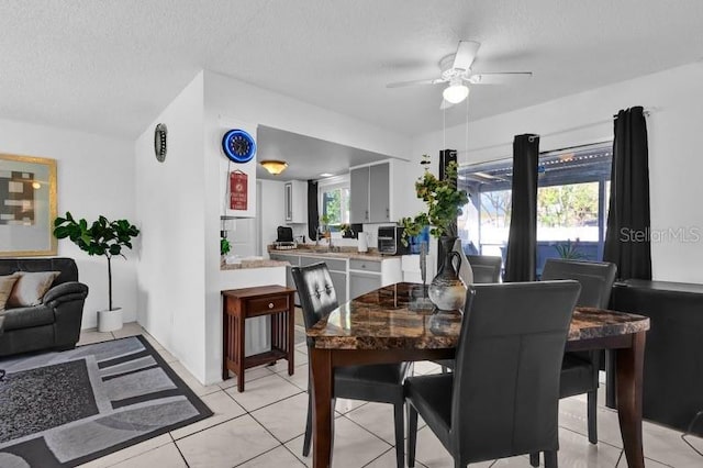 dining room with light tile patterned floors, a ceiling fan, and a textured ceiling