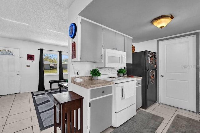 kitchen featuring gray cabinetry, light countertops, light tile patterned flooring, white appliances, and a textured ceiling