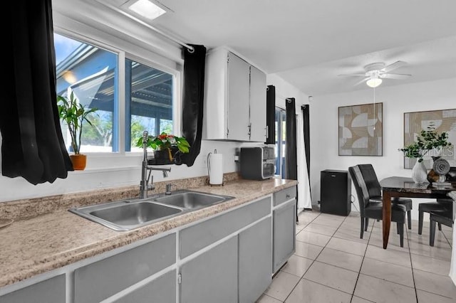 kitchen featuring light countertops, light tile patterned floors, a ceiling fan, and a sink