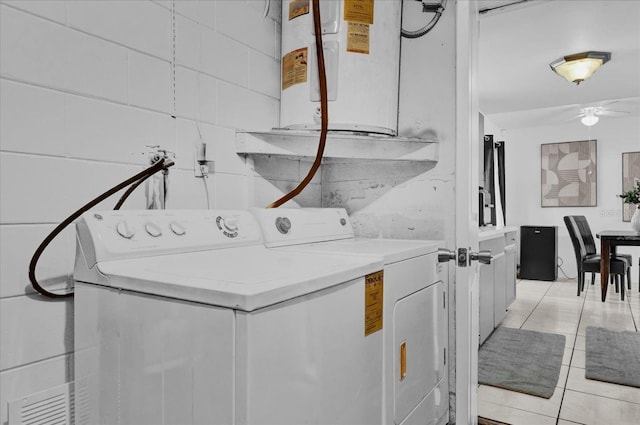 clothes washing area featuring light tile patterned floors, washer and clothes dryer, laundry area, and water heater