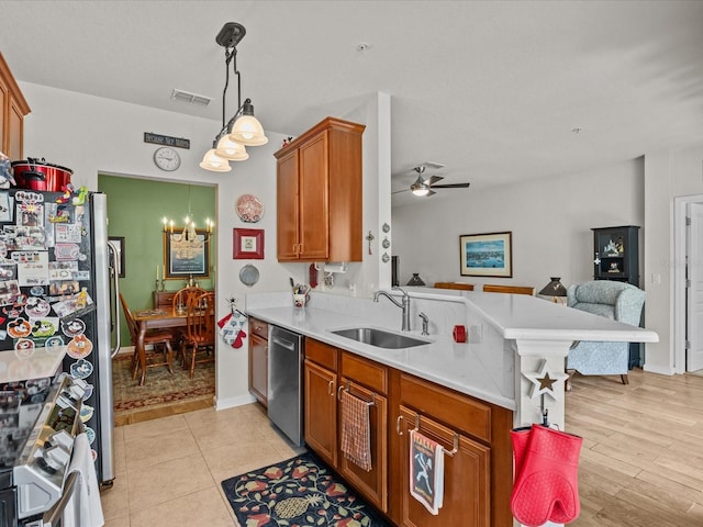 kitchen featuring brown cabinetry, open floor plan, light countertops, stainless steel appliances, and a sink