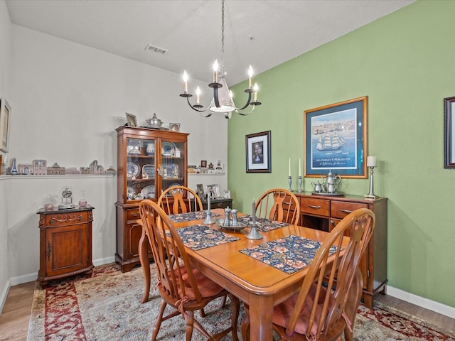 dining room featuring light wood finished floors, baseboards, visible vents, and a notable chandelier