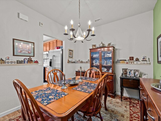 dining room featuring baseboards, visible vents, and a chandelier