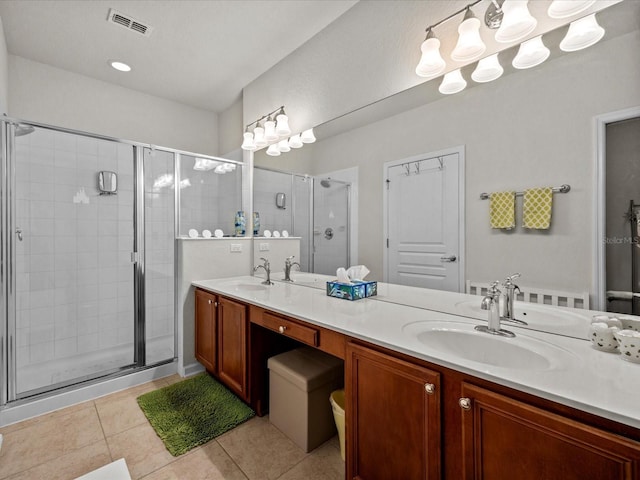 bathroom featuring double vanity, a stall shower, visible vents, tile patterned floors, and a sink