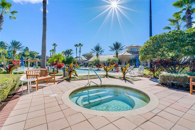 community pool with a patio area and a hot tub