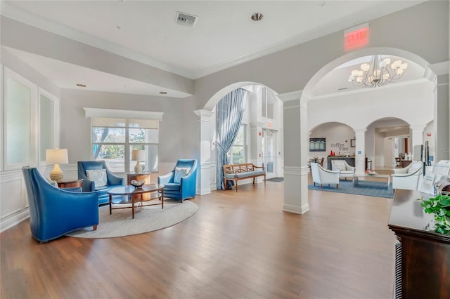 sitting room featuring decorative columns, visible vents, arched walkways, wood finished floors, and a decorative wall