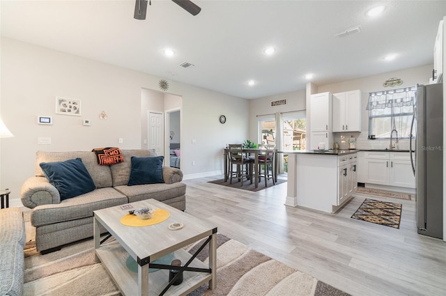 living room featuring light wood finished floors, baseboards, visible vents, and recessed lighting