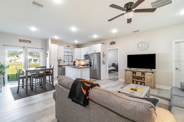 living area with light wood-type flooring, visible vents, and recessed lighting