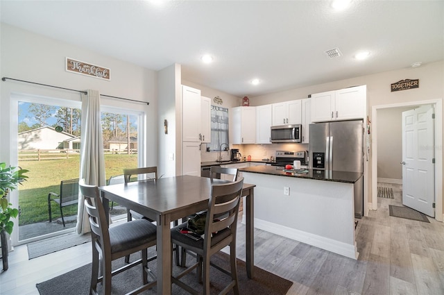 kitchen with a sink, visible vents, white cabinetry, appliances with stainless steel finishes, and light wood finished floors