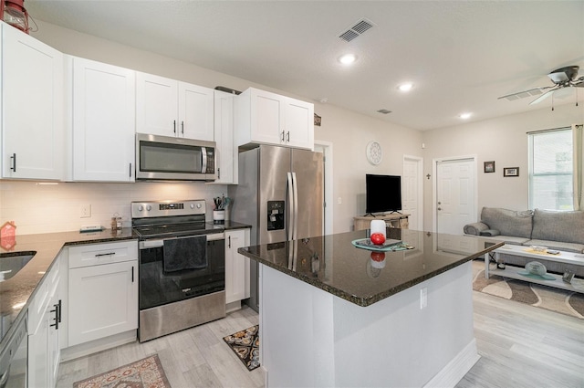 kitchen with visible vents, white cabinets, open floor plan, appliances with stainless steel finishes, and backsplash