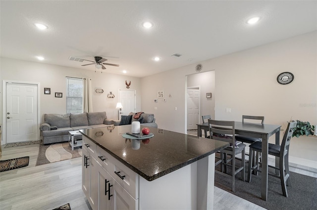 kitchen with recessed lighting, visible vents, light wood-style floors, white cabinetry, and a kitchen island