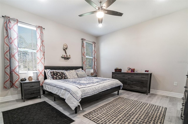 bedroom with light wood-style floors, baseboards, and a ceiling fan