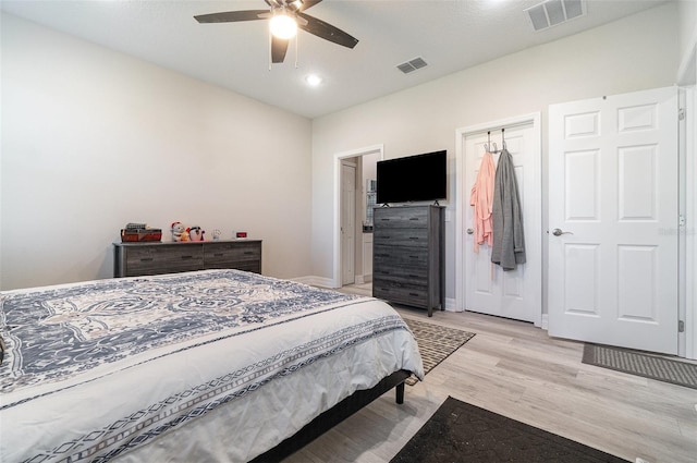 bedroom featuring baseboards, a ceiling fan, visible vents, and light wood-style floors