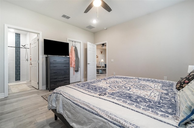 bedroom featuring light wood-style floors, a ceiling fan, visible vents, and connected bathroom