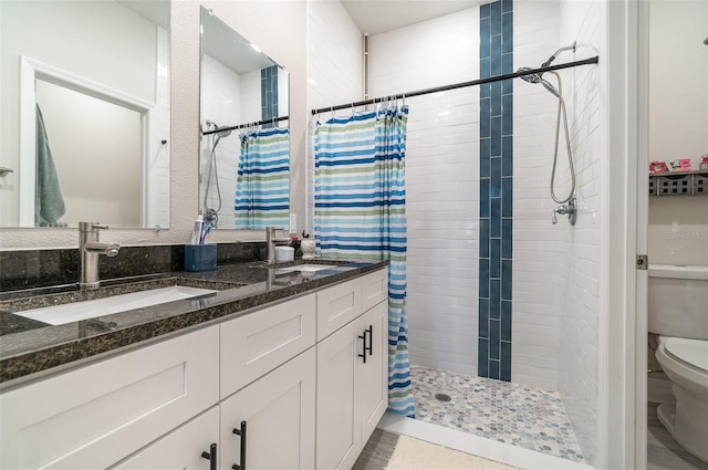 full bathroom with tiled shower, a sink, toilet, and double vanity