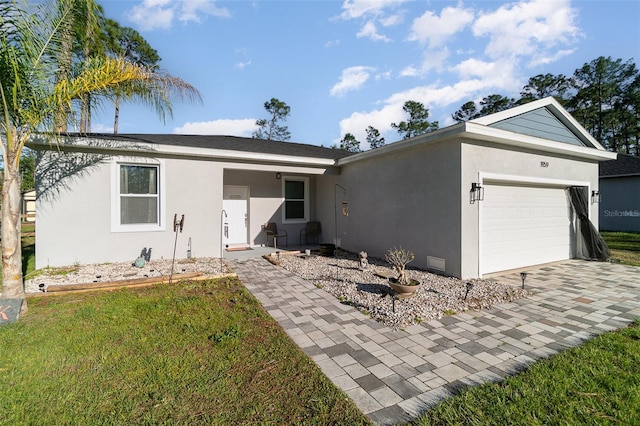 ranch-style home with a garage, decorative driveway, a front yard, and stucco siding